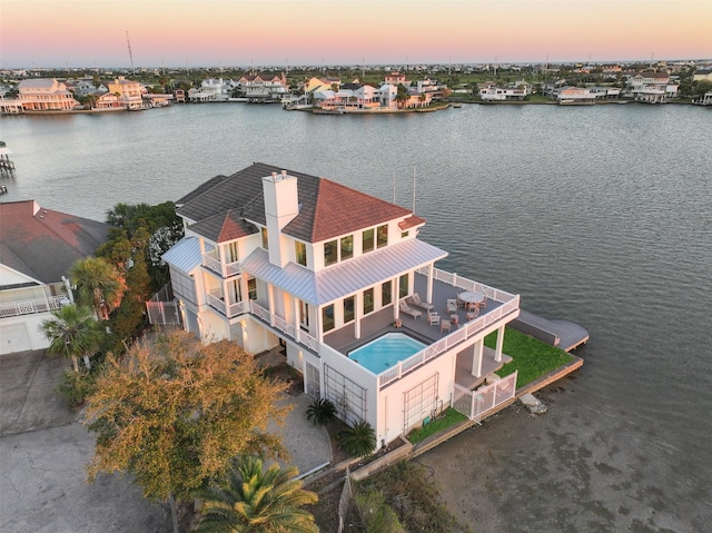 aerial view at dusk featuring a water view