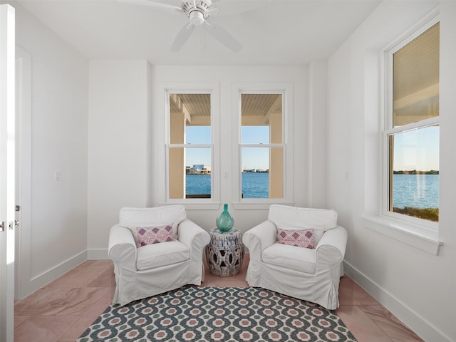 living area with a ceiling fan and baseboards