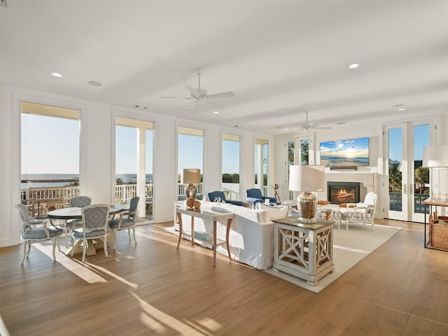 sunroom with a lit fireplace, ceiling fan, and a wealth of natural light