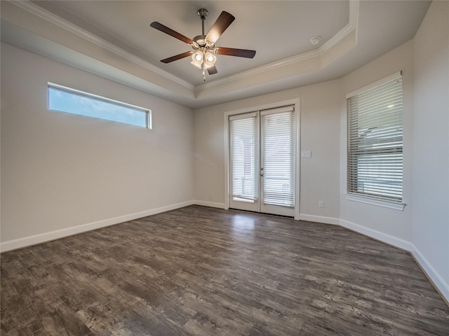 spare room with baseboards, a raised ceiling, and dark wood finished floors