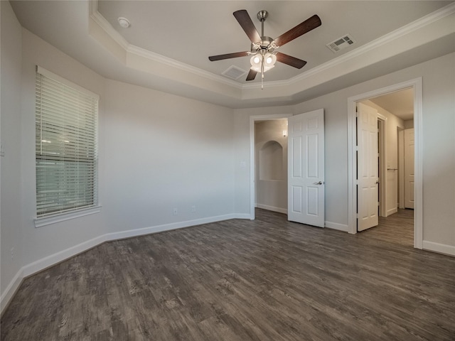 unfurnished bedroom with a raised ceiling, dark wood-style floors, visible vents, and arched walkways