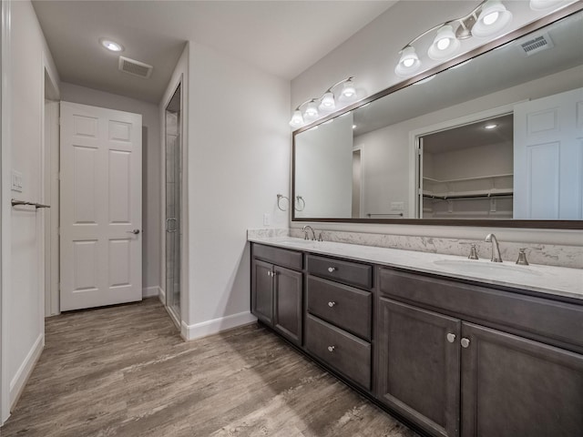 bathroom with wood finished floors, visible vents, and a sink