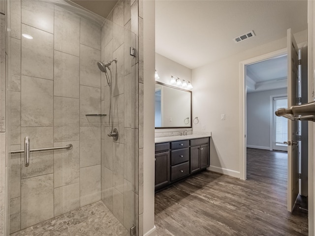 full bathroom featuring baseboards, wood finished floors, visible vents, and a stall shower