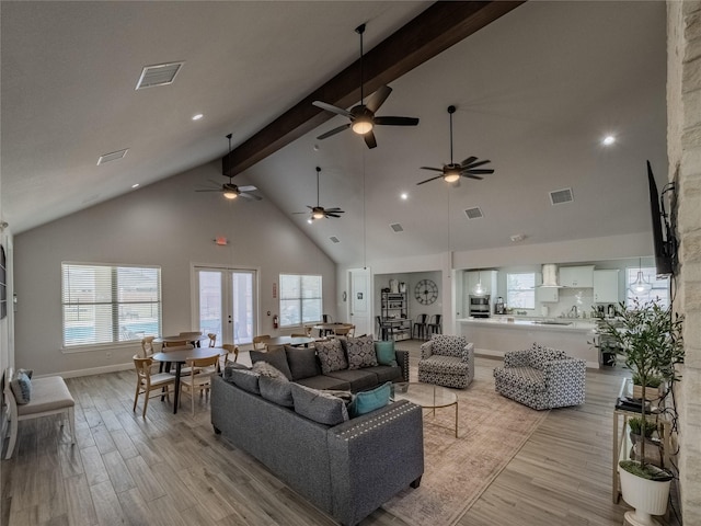 living room featuring beamed ceiling, light wood-style flooring, visible vents, and french doors