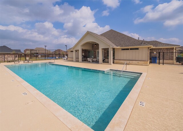 community pool with fence and a patio area