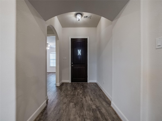 entryway with dark wood finished floors, arched walkways, visible vents, and baseboards