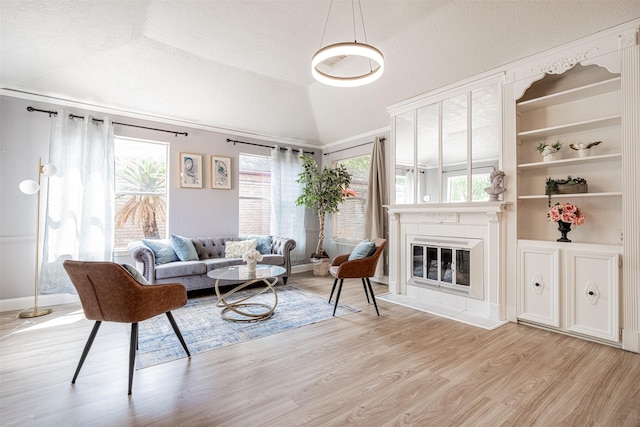 living room featuring lofted ceiling, a textured ceiling, light wood-type flooring, and a glass covered fireplace