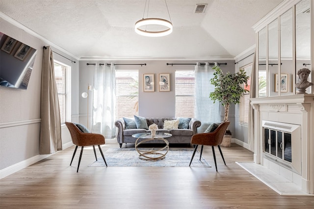 living area featuring vaulted ceiling, light wood finished floors, and visible vents