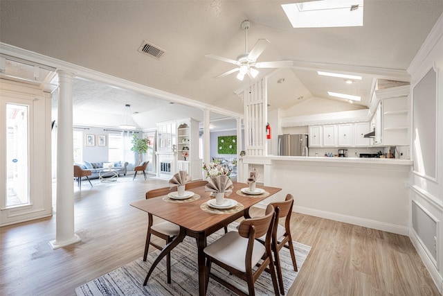 dining room featuring light wood-style floors, decorative columns, visible vents, and lofted ceiling with skylight