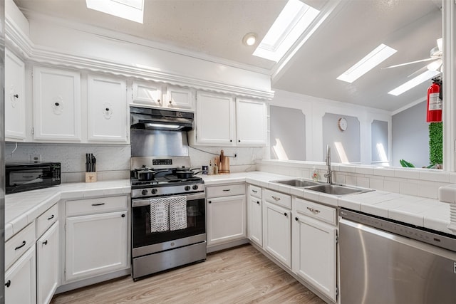 kitchen featuring appliances with stainless steel finishes, white cabinetry, a sink, and under cabinet range hood