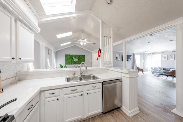 kitchen featuring a sink, decorative columns, open floor plan, and stainless steel dishwasher