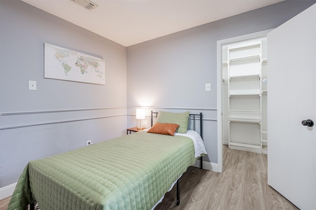 bedroom with visible vents, a spacious closet, baseboards, and wood finished floors