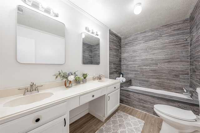 bathroom with a textured ceiling, double vanity, wood finished floors, and a sink