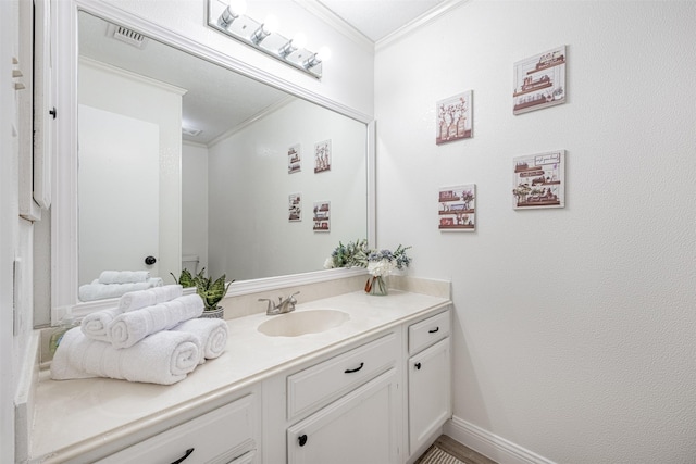 bathroom with visible vents, crown molding, vanity, and baseboards