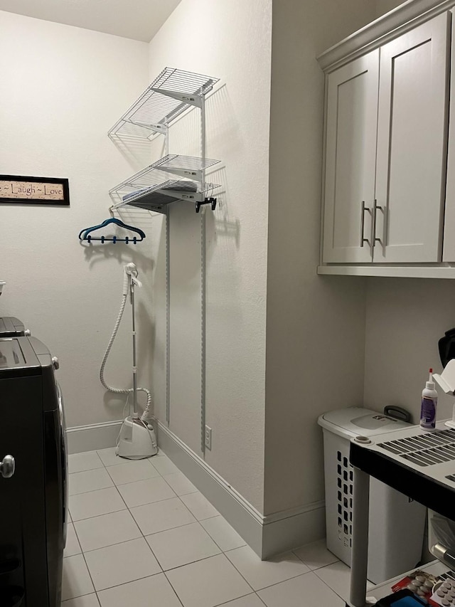 clothes washing area featuring washer and dryer, cabinet space, baseboards, and light tile patterned floors