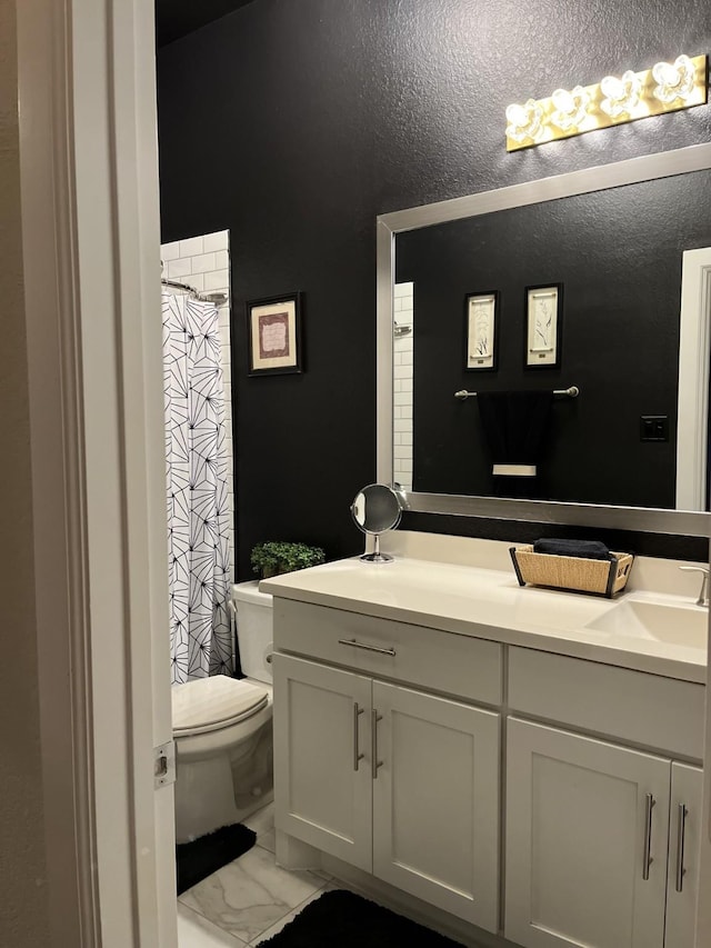 bathroom featuring marble finish floor, double vanity, toilet, a sink, and a shower with curtain