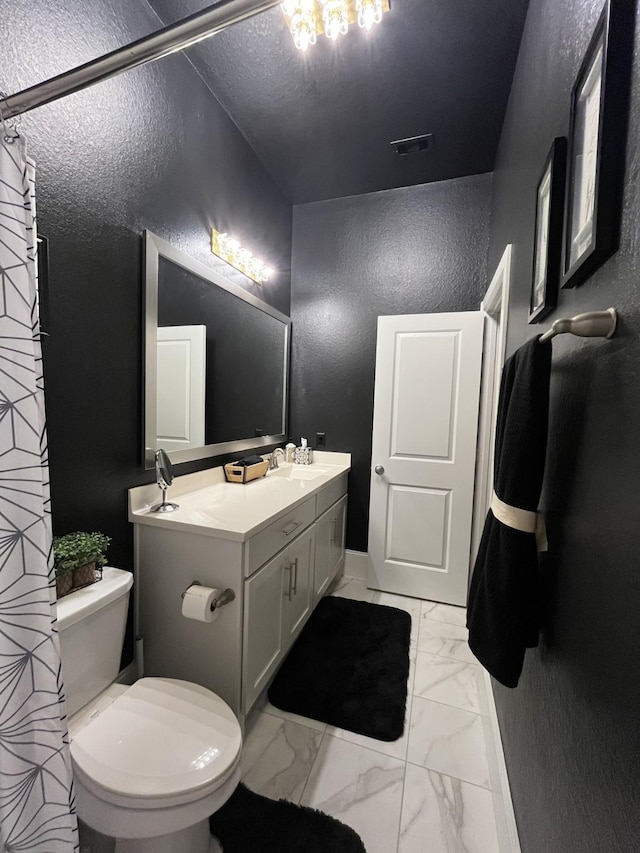 bathroom featuring visible vents, a textured wall, toilet, marble finish floor, and vanity