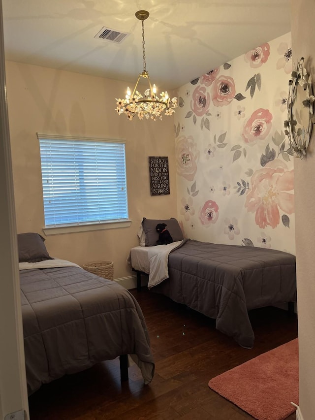 bedroom with a notable chandelier, visible vents, and wood finished floors