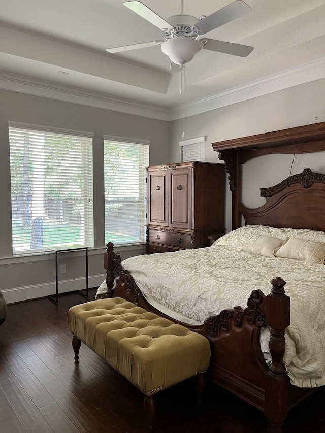 bedroom featuring a raised ceiling, wood-type flooring, ornamental molding, a ceiling fan, and baseboards