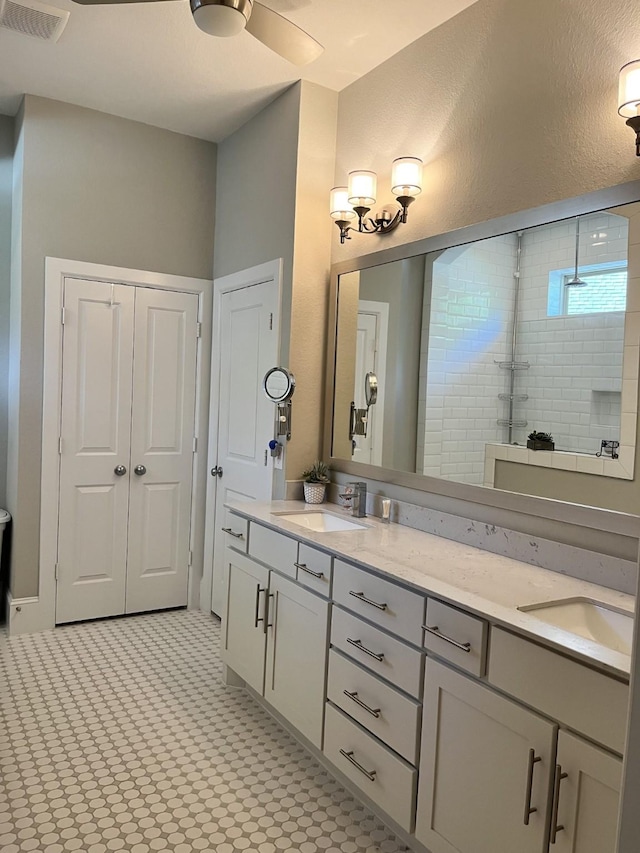 bathroom featuring double vanity, visible vents, a sink, and tiled shower