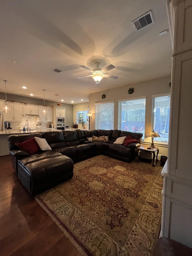 living room featuring dark wood-style floors, ceiling fan, visible vents, and recessed lighting