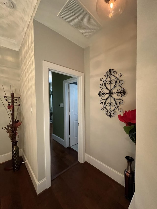 hallway featuring dark wood finished floors, visible vents, and baseboards