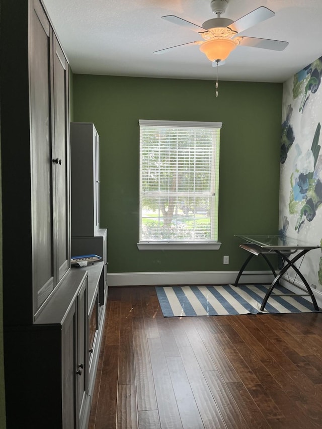 interior space featuring a ceiling fan, dark wood finished floors, and baseboards