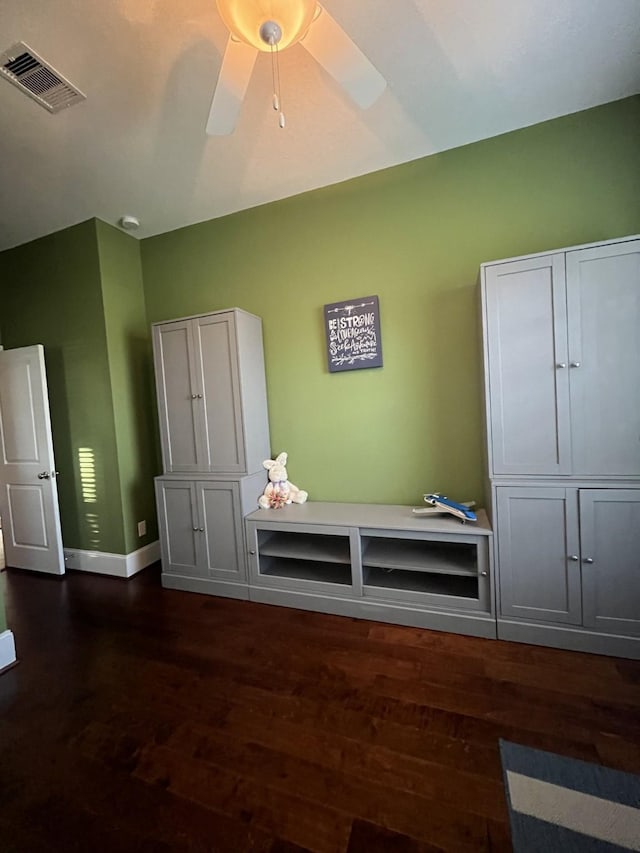 interior space with dark wood-type flooring, visible vents, baseboards, and a ceiling fan