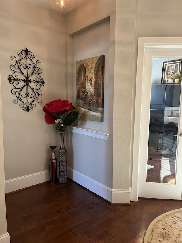 corridor featuring wood-type flooring and baseboards