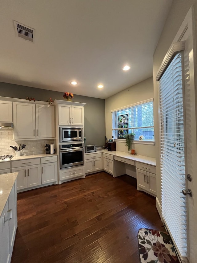 kitchen with tasteful backsplash, visible vents, dark wood finished floors, built in study area, and appliances with stainless steel finishes