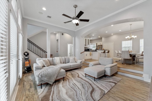 living area with stairs, visible vents, light wood finished floors, and ornamental molding