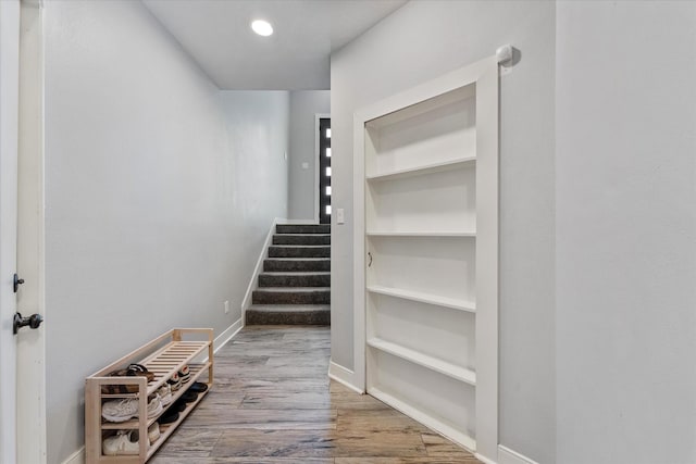 stairway with recessed lighting, built in features, wood finished floors, and baseboards