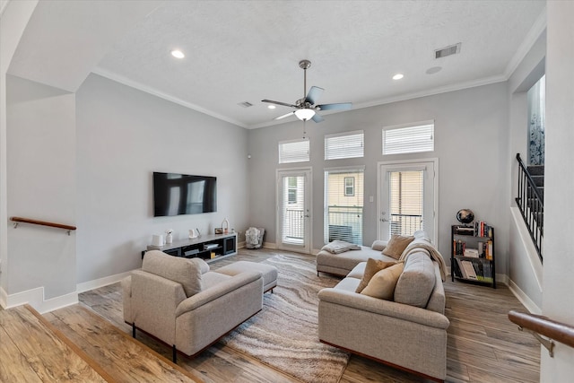 living area with baseboards, wood finished floors, and crown molding