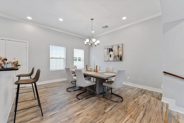 dining room featuring visible vents, an inviting chandelier, crown molding, light wood finished floors, and baseboards