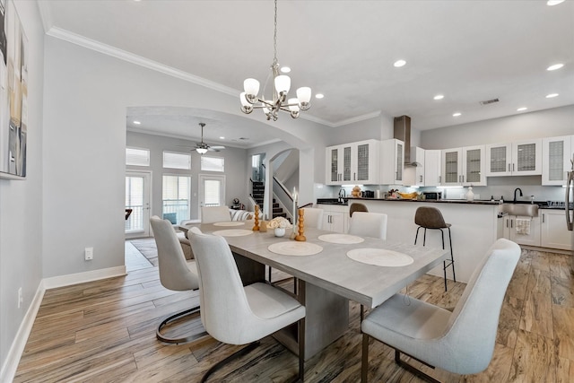 dining room featuring baseboards, ornamental molding, recessed lighting, light wood-style flooring, and arched walkways