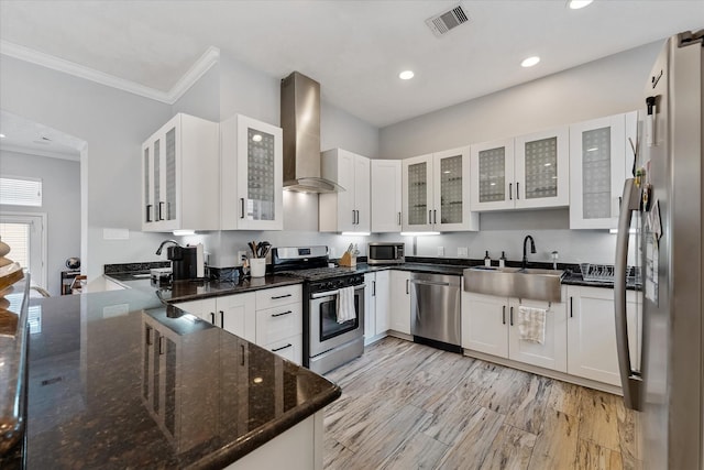 kitchen featuring visible vents, crown molding, wall chimney range hood, stainless steel appliances, and a sink