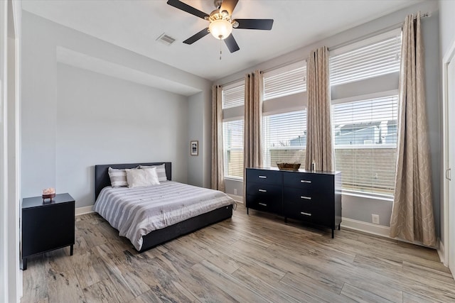 bedroom with a ceiling fan, light wood-style flooring, baseboards, and visible vents