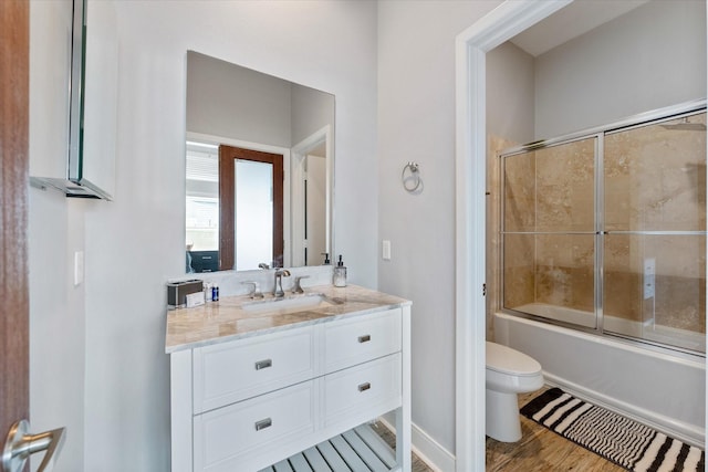 bathroom with enclosed tub / shower combo, toilet, wood finished floors, and vanity