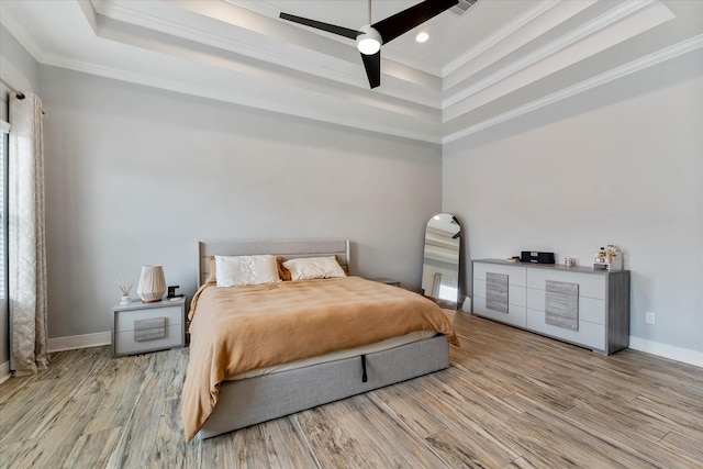 bedroom featuring crown molding, ceiling fan, baseboards, wood finished floors, and a raised ceiling