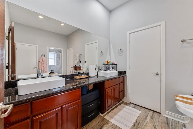 bathroom featuring double vanity, recessed lighting, wood finished floors, and a sink