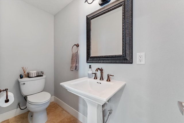 bathroom with a sink, baseboards, toilet, and tile patterned floors