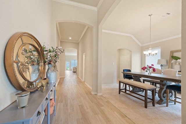 dining room with arched walkways, a notable chandelier, visible vents, light wood-style floors, and ornamental molding