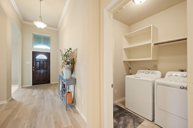 laundry room featuring laundry area, crown molding, light wood finished floors, and washing machine and clothes dryer