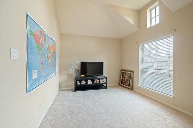 carpeted living area featuring a high ceiling, a wealth of natural light, and baseboards