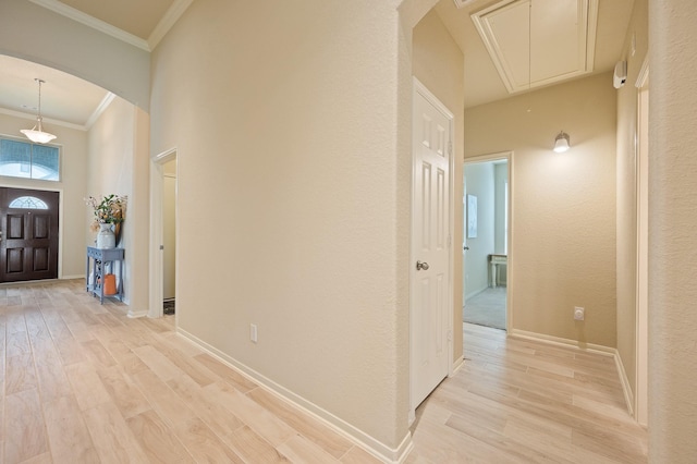 foyer entrance featuring light wood finished floors, baseboards, arched walkways, and crown molding