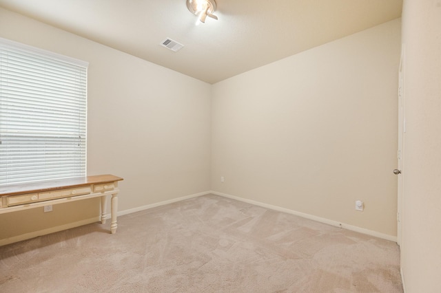 empty room with visible vents, light carpet, and baseboards