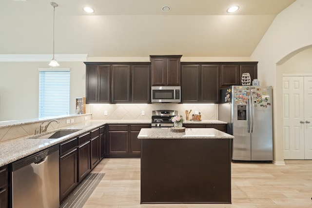 kitchen with dark brown cabinetry, light wood finished floors, vaulted ceiling, stainless steel appliances, and a sink