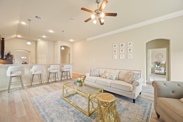 living area with light wood-style floors, visible vents, arched walkways, and a ceiling fan