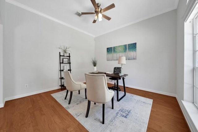 dining area featuring baseboards, wood finished floors, a ceiling fan, and crown molding