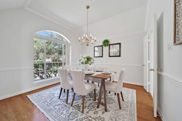 dining area with baseboards, vaulted ceiling, wood finished floors, and a chandelier